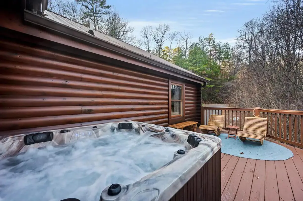 An outdoor hot tub nestled on a wooden deck, surrounded by lounge chairs and with views of nature. The tranquil setting invites guests to soak under the stars, combining the luxury of a spa with the beauty of the outdoors.