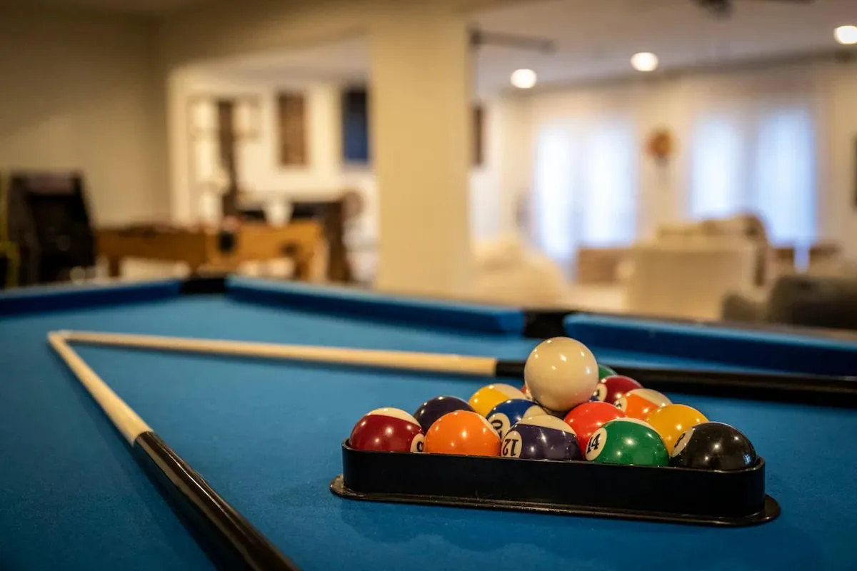 A lively game room featuring a pool table with billiard balls and a cue stick ready for play. The setting is bright and welcoming, ideal for socializing and unleashing your competitive spirit during game nights.